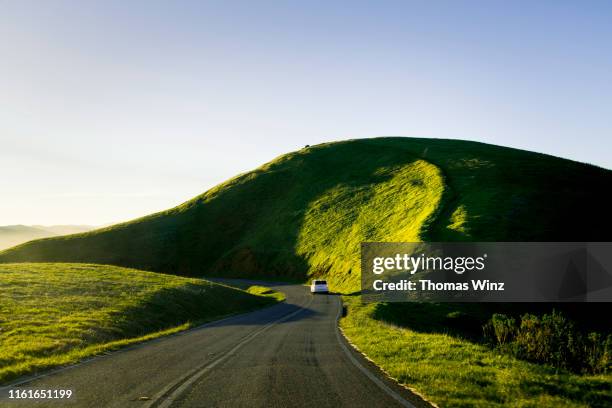 curving road and hillside - country roads stock-fotos und bilder