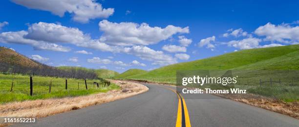 country road through rolling hills - panoramic sky stock pictures, royalty-free photos & images