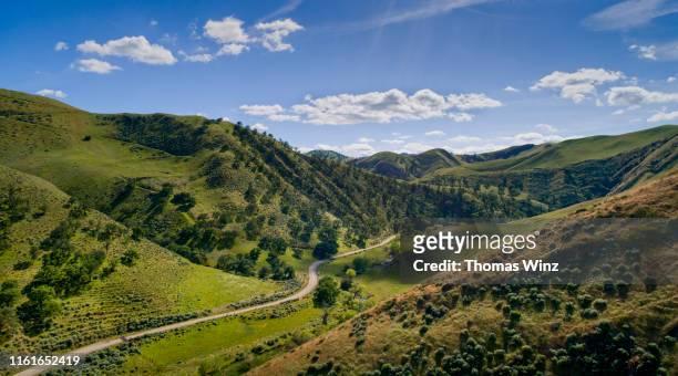 road through a valley from above - green hills fotografías e imágenes de stock