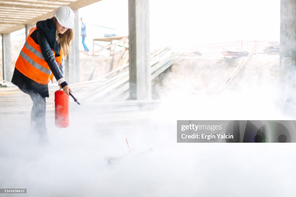 Female construction worker with a fire extinguisher on construction site