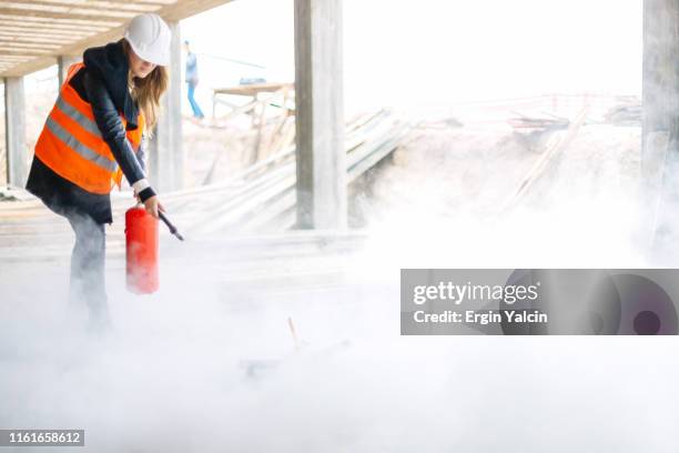 trabalhador da construção fêmea com um extintor de incêndio no canteiro de obras - extintor de incêndio - fotografias e filmes do acervo