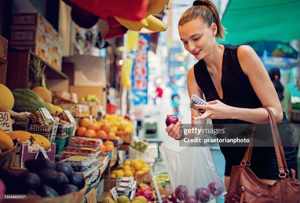 Young girl is buying fruits and vegetables at traditional marketplace