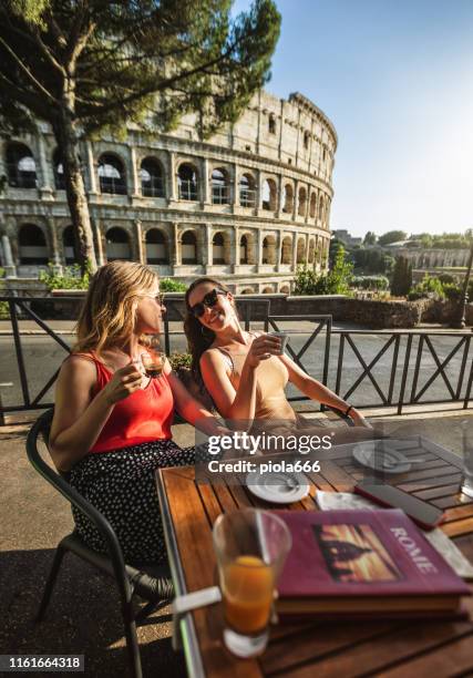 mujeres turistas en la cafetería bajo el coliseo de roma - roma fotografías e imágenes de stock