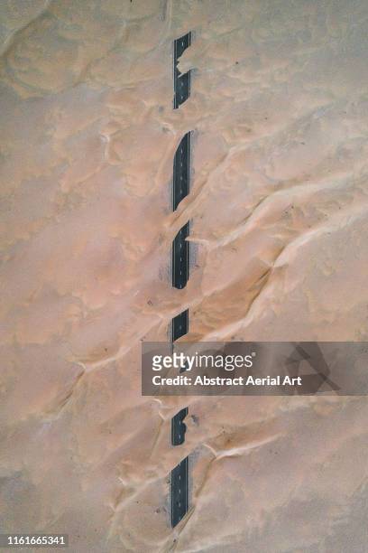 Dunes crossing a straight road in the desert, Dubai, United Arab Emirates