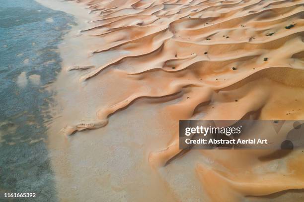 winding sand dunes on edge of the desert, united arab emirates - united arab emirates aerial stock pictures, royalty-free photos & images