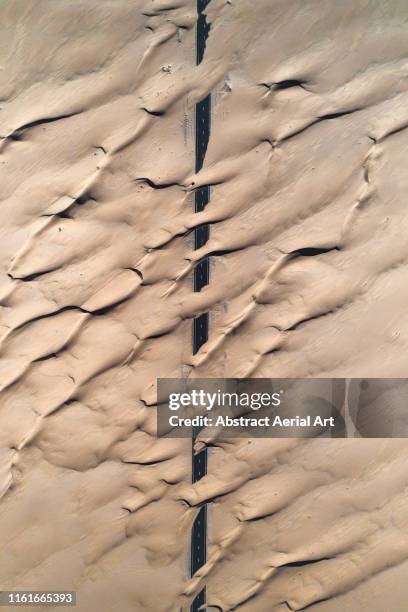 abstract patterns crossing a desert road taken by drone, united arab emirates - sand art stock pictures, royalty-free photos & images