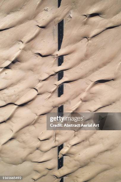top down aerial shot of a desert road and windswept sand dunes crossing it, united arab emirates - persian gulf countries stock pictures, royalty-free photos & images