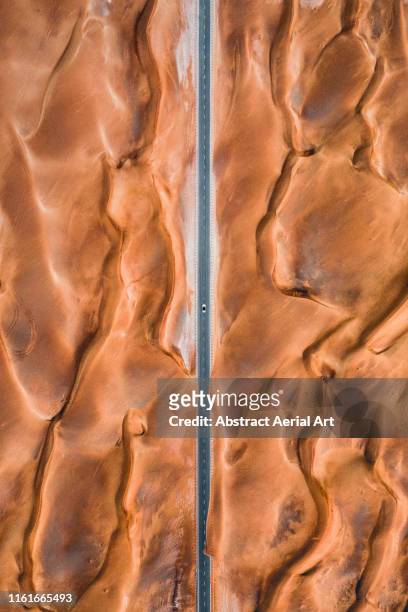 Road through the centre of fiery coloured desert patterns shot from above, United Arab Emirates