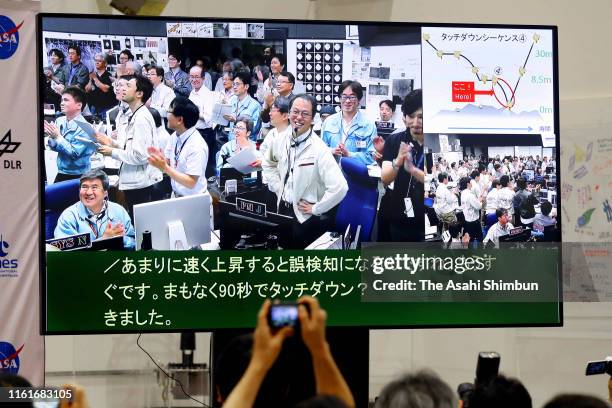 Press room monitor shows applause breaking out in the control room of the Sagamihara complex of the Japan Aerospace Exploration Agency after...