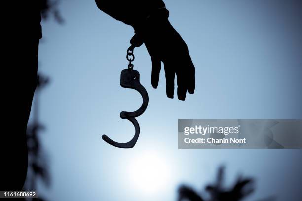 cropped hand of men removing handcuffs - handcuffs photos et images de collection