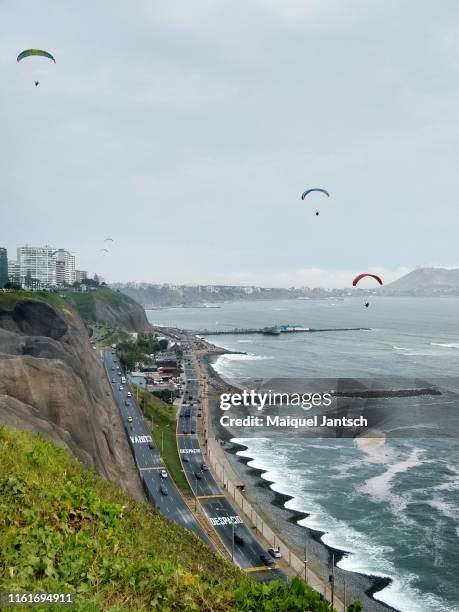 people flying in a hang gliding along the cliffs of miraflores district in lima, peru. - lima perú stock-fotos und bilder