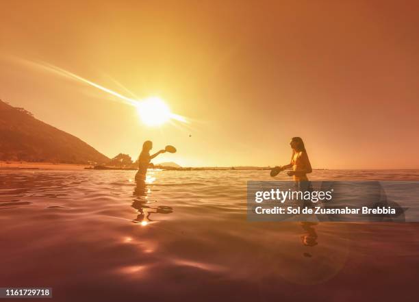 teenage sisters playing tennis in the sea on a wonderful sunset - idyllic stock pictures, royalty-free photos & images