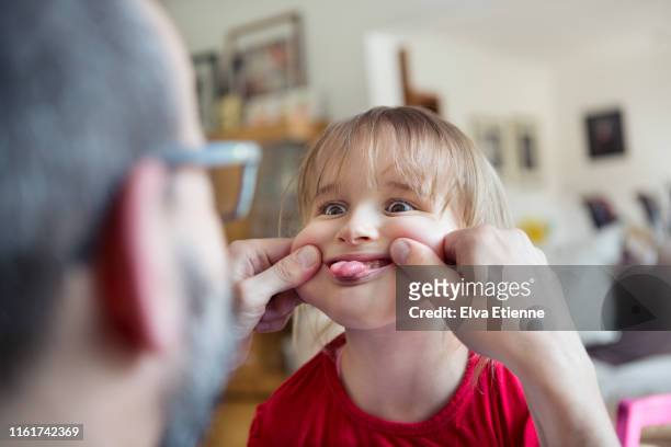 mischievious child making silly face at father in a home environment - pressure photos et images de collection