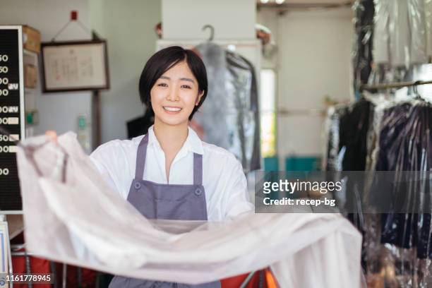 young woman working at dry cleaning shop - dry cleaned stock pictures, royalty-free photos & images
