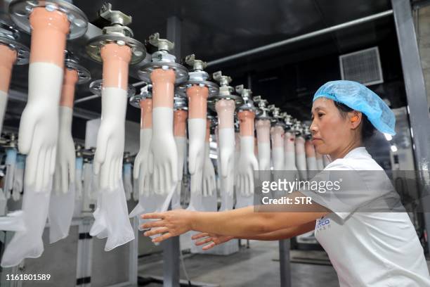 This photo taken on August 14, 2019 shows an employee working on a medical glove production line at a factory in Huaibei in China's eastern Anhui...