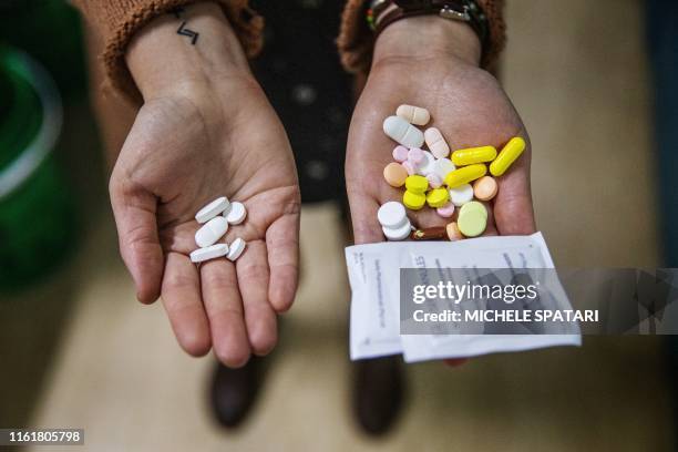 Pharmacist holds two sets of pills in her hands, showing the difference between the amount of tablets a patient takes on the new NIX course versus...