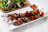 Pork kebabs skewers with sauce and salad.