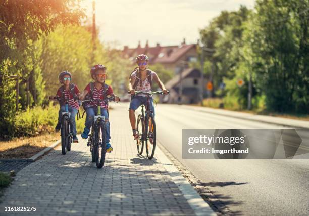 kids riding bikes to school - sports helmet stock pictures, royalty-free photos & images