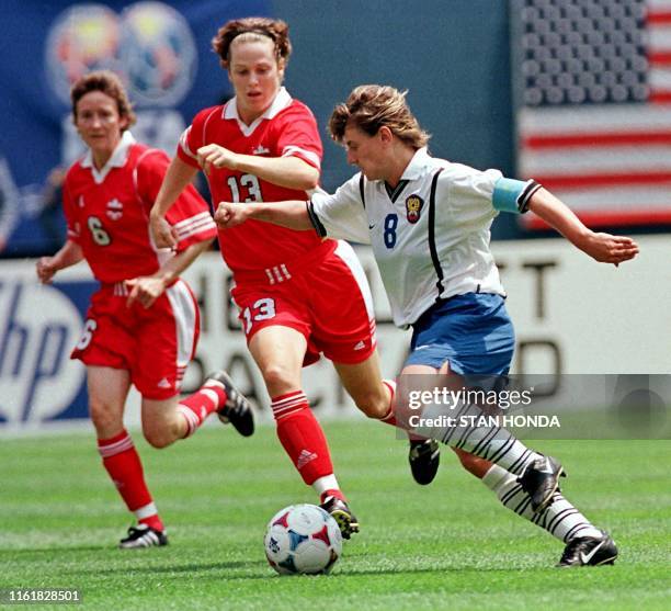 Irina Grigorieva of Russia pushes the ball past Canadians Amy Walsh and Geri Donnelly in the first half in the first round of Women's World Cup 26...