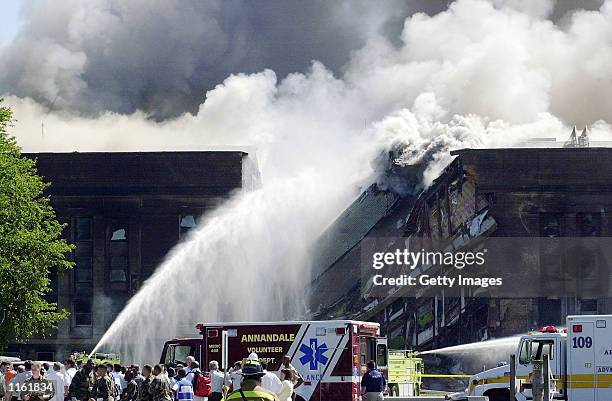 Fire fighters struggle to contain a spreading fire after a highjacked commercial jetliner crashed into the Pentagon September 11, 2001 in Arlington,...