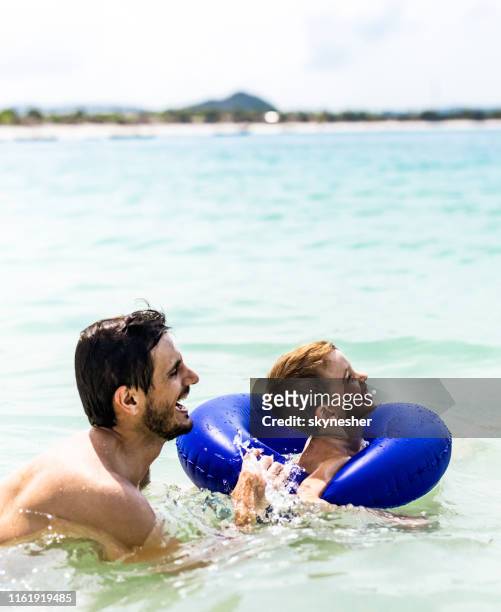 gelukkige alleenstaande vader plezier tijdens het zwemmen met zijn zoon in zee. - zwemband stockfoto's en -beelden