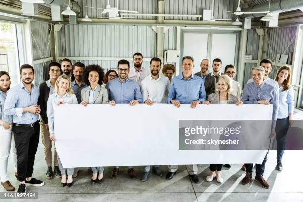 crowd of happy business people holding a banner in a board room. - employee engagement banner stock pictures, royalty-free photos & images
