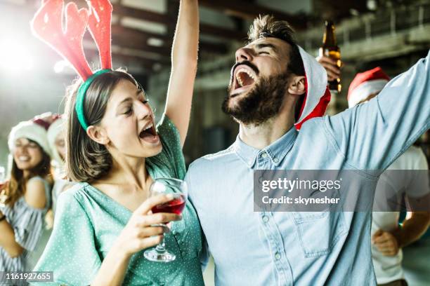 happy couple having fun while singing on christmas party. - christmas party office stock pictures, royalty-free photos & images