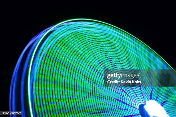 long exposure of a ferris wheel with blue and green lights from the side. - bunte festival night stock-fotos und bilder