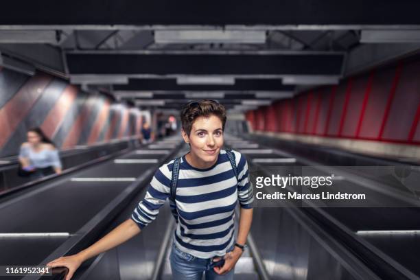 vrouw op een roltrap in een metrostation - escalator stockfoto's en -beelden