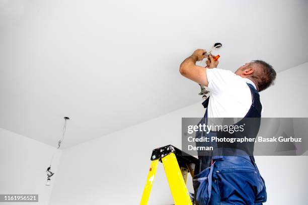 a repairman / a male electrician is fixing the light. installing led light into ceiling fixture. - ceiling lamp stockfoto's en -beelden
