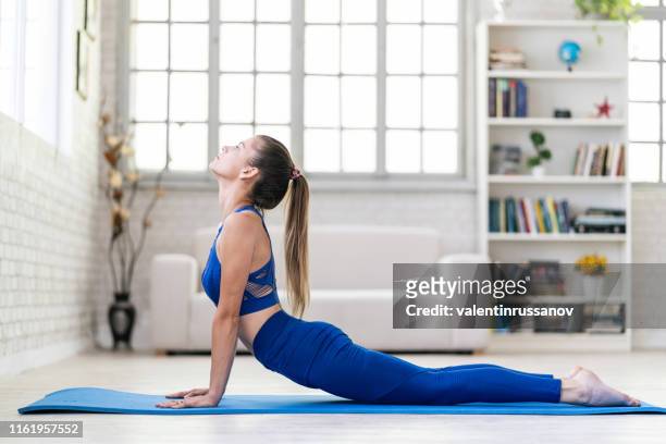 junge sportliche frau übt yoga, tun nach oben gerichtet hund übung - practice stock-fotos und bilder