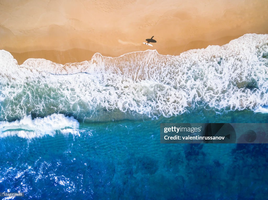 Aerial view of surfer going into the sea