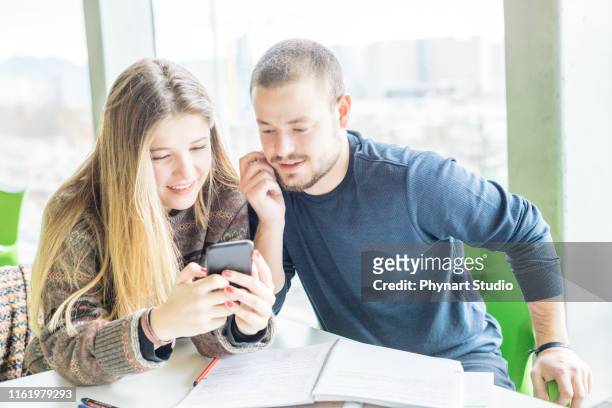 two people studying together using their smart phones as a resource - electronic workbook stock pictures, royalty-free photos & images