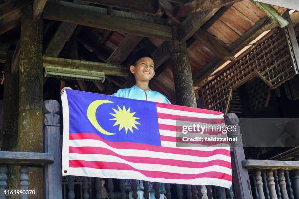 マレーシアの旗を持つマレー人イスラム教徒の少年 - マレーシア独立記念日 ストックフォトと画像