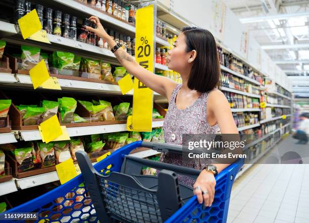 frau beim einkaufen, ziehen von einkaufswagen in einem supermarkt - supermarket trolley female stock-fotos und bilder