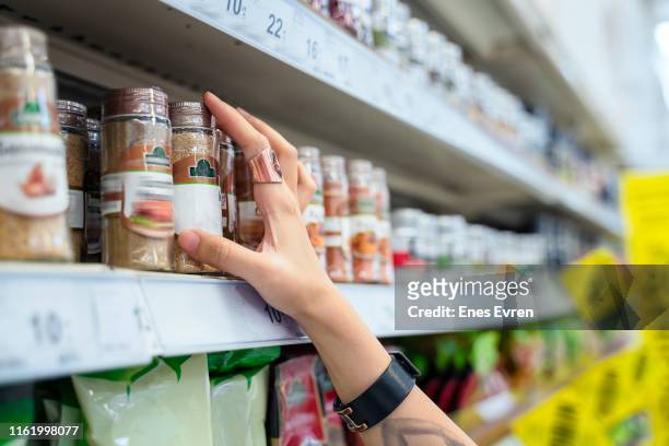 nahaufnahme der frau hand einkaufen im supermarkt, pfeffer im regal pflücken - gewürz stock-fotos und bilder