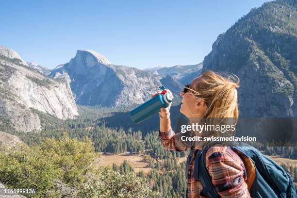 young woman on top of yosemite valley, usa drinking water from reusable bottle - reusable stock pictures, royalty-free photos & images