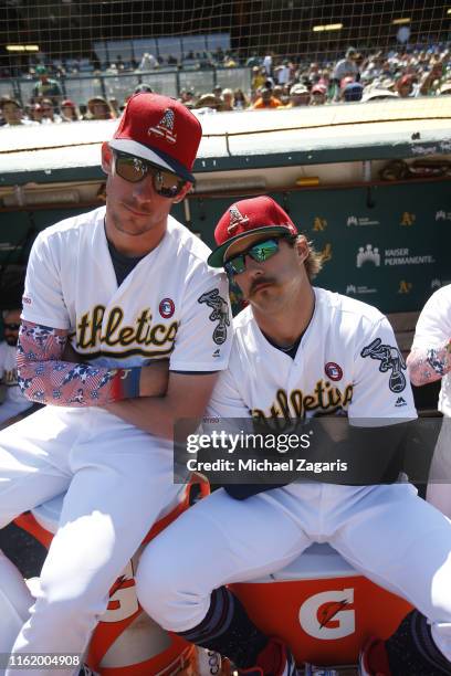 Chris Bassitt and Daniel Mengden of the Oakland Athletics sit in the dugout during the game against the Minnesota Twins at the Oakland-Alameda County...