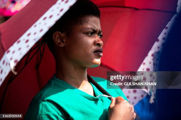 Neliswa Kekela holds an umbrella as she stands near Wonderkop in Marikana, Rustenburg, where striking miners were killed during the Marikana...