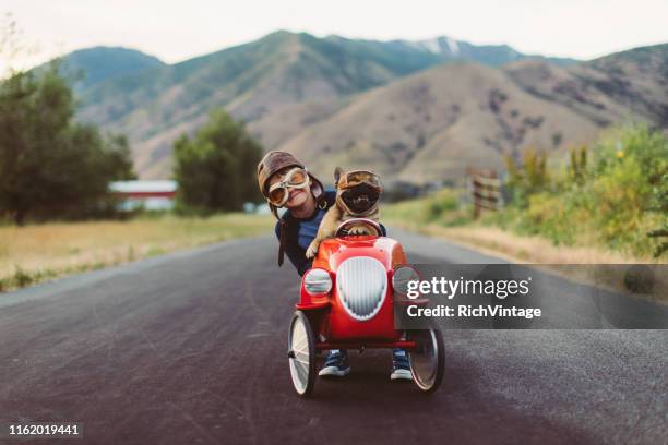 boy and dog in toy racing car - flying goggles stock pictures, royalty-free photos & images