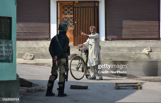 Indian paramilitary policeman stops a Kashmiri man from crossing the road during curfew in Srinagar, Indian Administered Kashmir on 06 August 2019....