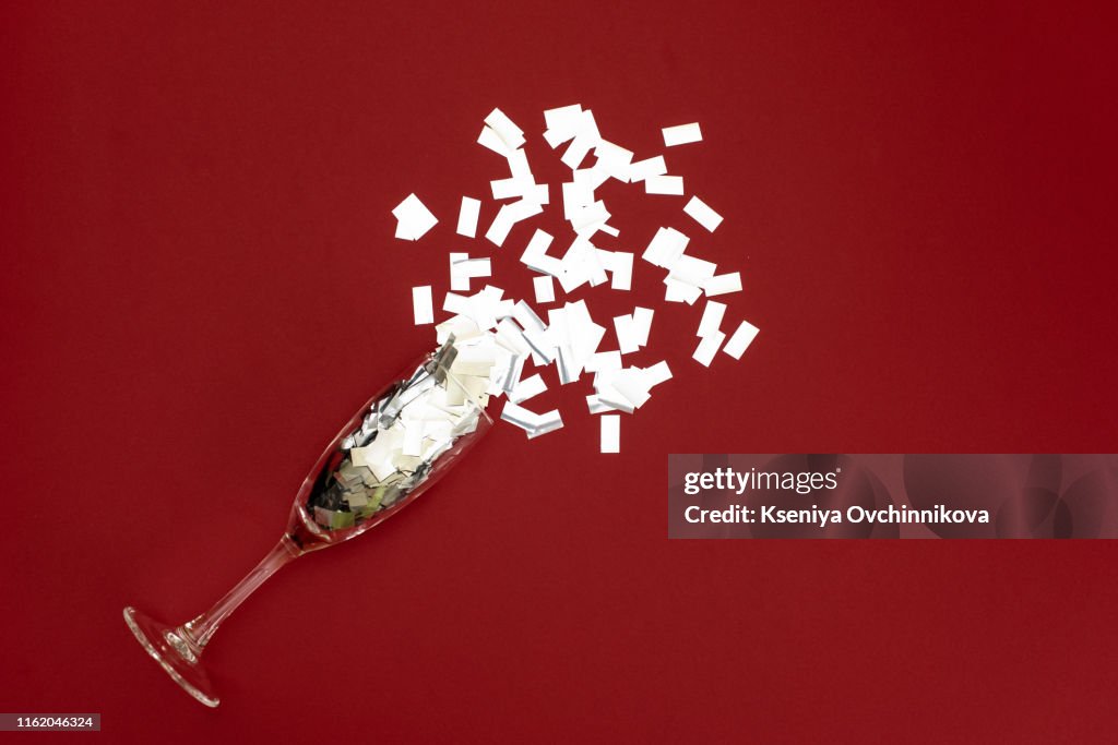 A glass of champagne on a pink background with confetti