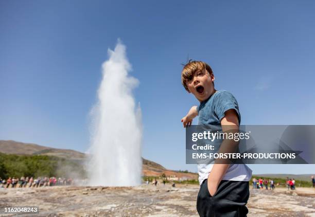 young boy is watching geysir stokkur - geysir stock-fotos und bilder