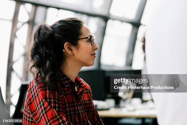 young woman listening during meeting at work - one mid adult woman only fotografías e imágenes de stock