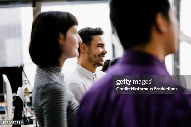 young man smiling while listening during meeting - lilac stock pictures, royalty-free photos & images