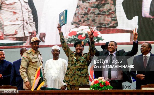 Sudan's protest leader Ahmad Rabie , flashes the victory gesture alongside General Abdel Fattah al-Burhan , the chief of Sudan's ruling Transitional...