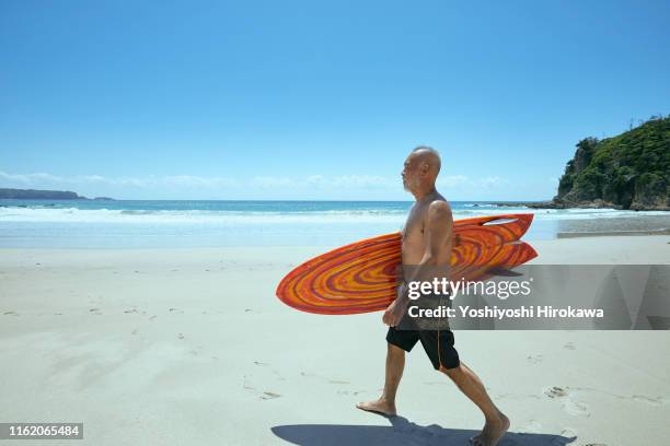 senior surfer walking beach - mature surfers stock pictures, royalty-free photos & images