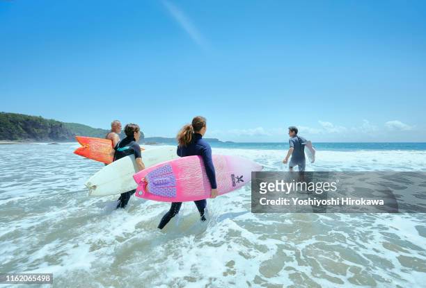 senior surfers running towards the sea - four people stock pictures, royalty-free photos & images