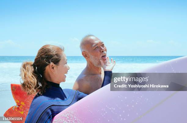 senior couple walking beach - japanese couple beach stock-fotos und bilder