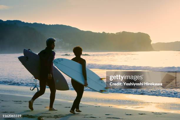 silhouette of senior couple surfer with surfboard - couple voyage sport photos et images de collection